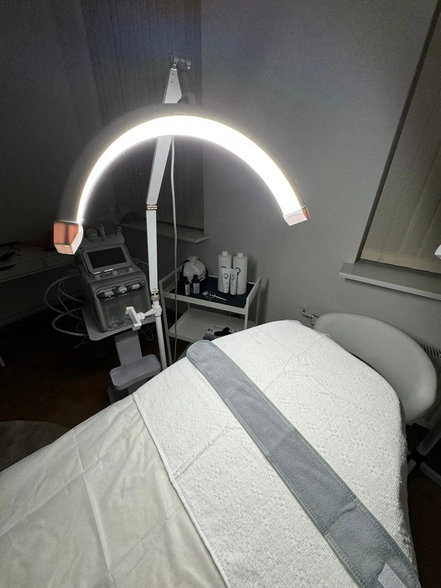 An LED ring lamp above the treatment bed