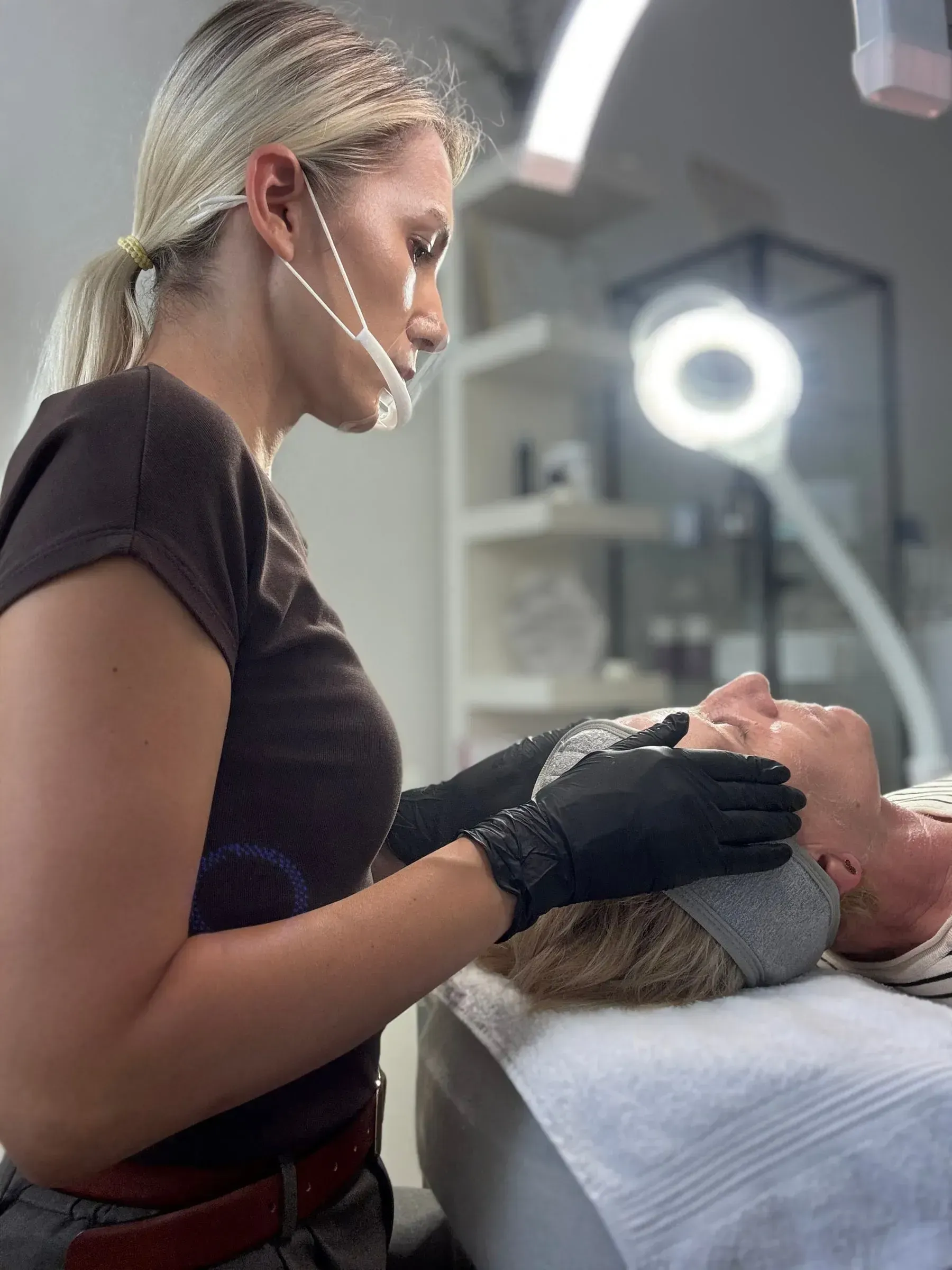 A microneedling treatment on a client's face under an LED ring light