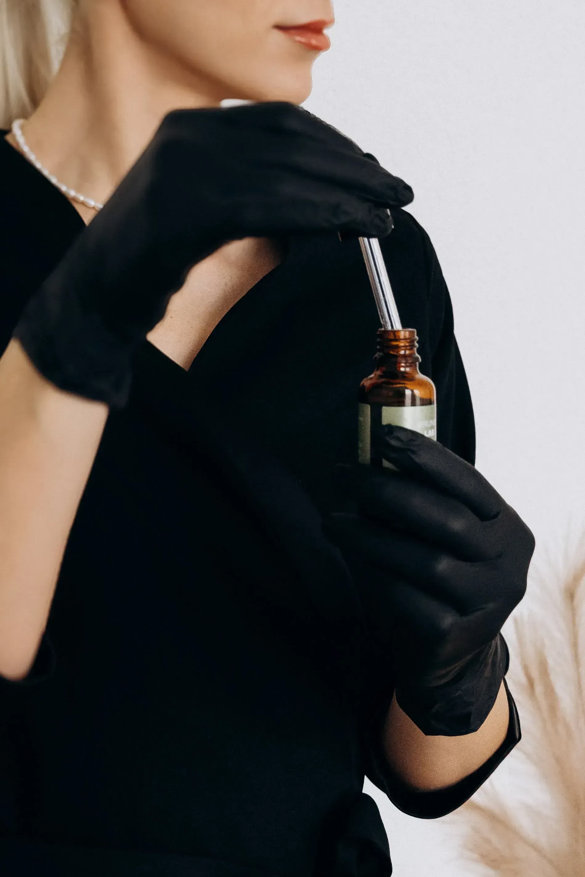 Gloved hands holding a serum dropper — product close-up